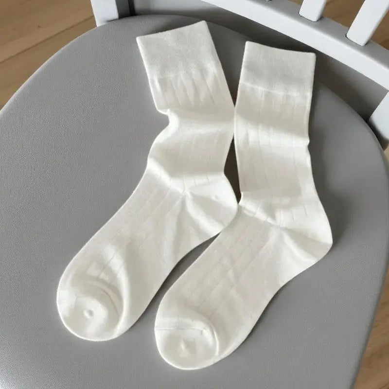 Chaussettes en bambou côtelées blanches et grises pour femme, présentation à plat sur chaise claire.