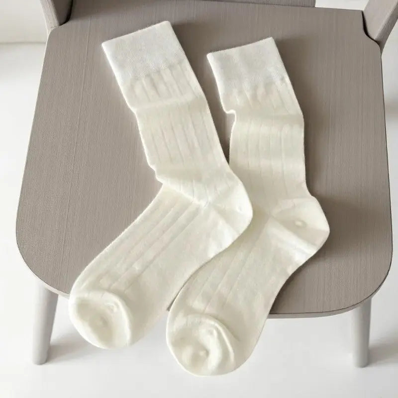 Paire de chaussettes hautes blanches en bambou pour femme, motif côtelé, posées sur une chaise grise.