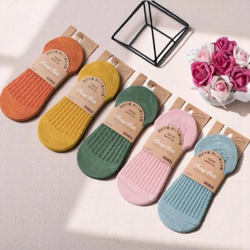 Ensemble de chaussettes invisibles colorées pour femme, ambiance lumineuse et estivale avec fleurs en décoration.
