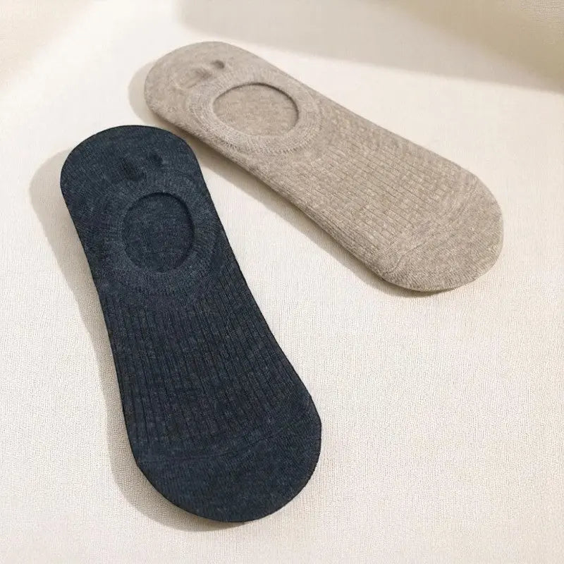 Chaussettes invisibles femme noir et beige posées à plat sur tissu clair, parfaites pour un confort discret au quotidien.