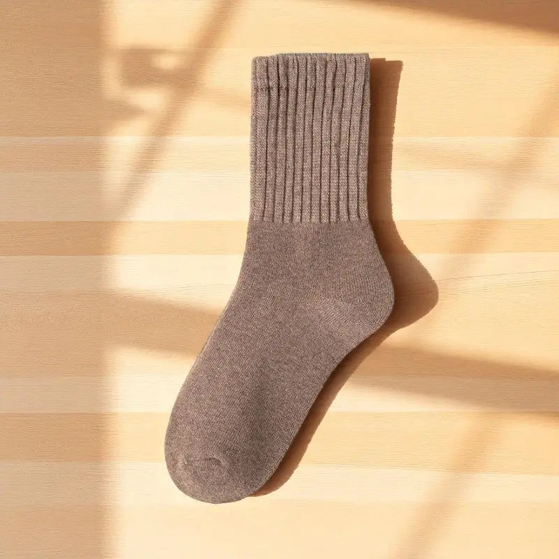 Chaussette marron en laine éclairée par la lumière naturelle.