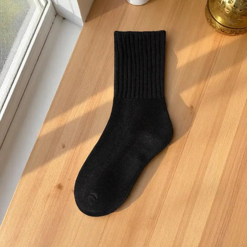 Chaussette noire en laine exposée à la lumière d’une fenêtre.