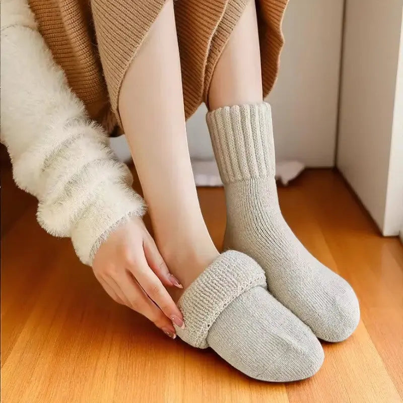 Femme en tenue cocooning portant des chaussettes en laine beige.
