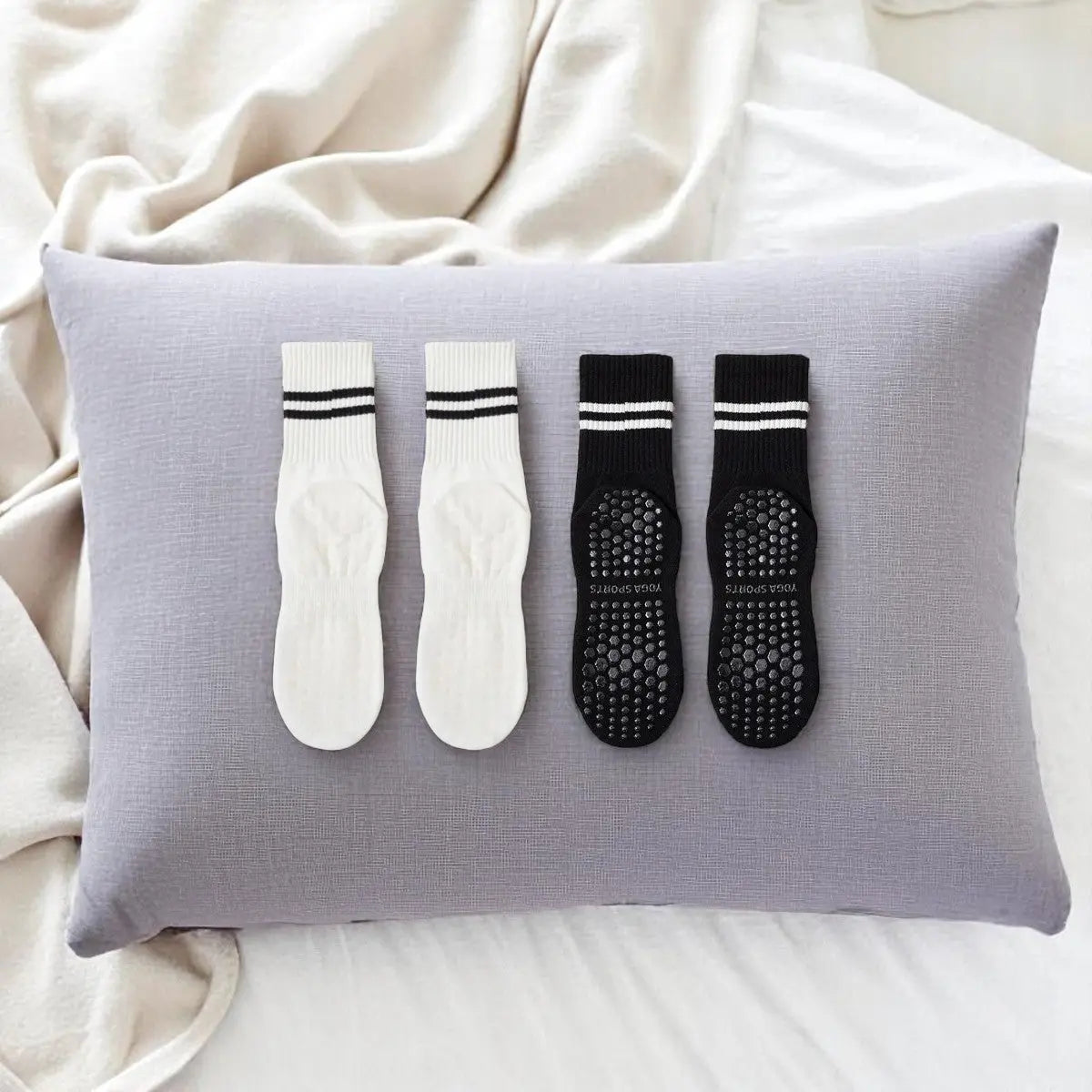 Duo de chaussettes antidérapantes femme noir et blanc disposé sur un coussin, design élégant et pratique.