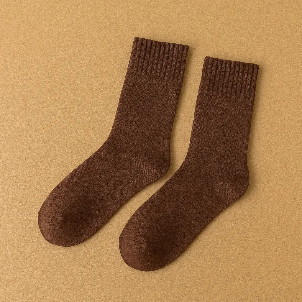 Chaussettes marron foncé en cachemire pour homme sur un tapis beige.