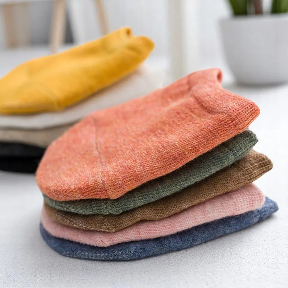 Zoom sur un lot de chaussettes invisibles demi-pied empilées, avec une chaussette orange en premier plan.