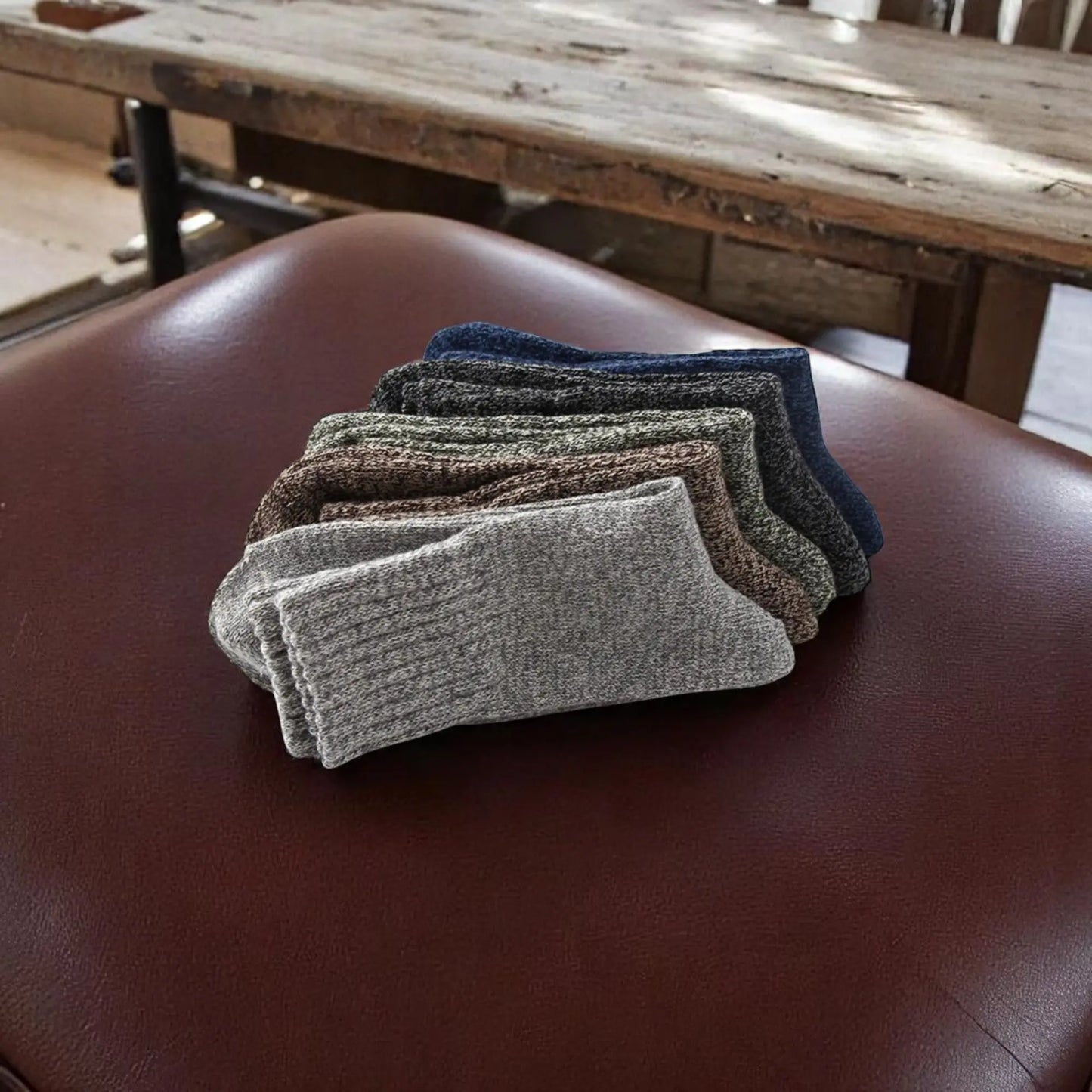 Chaussettes épaisses pour homme en 5 couleurs, posées sur un siège en cuir.