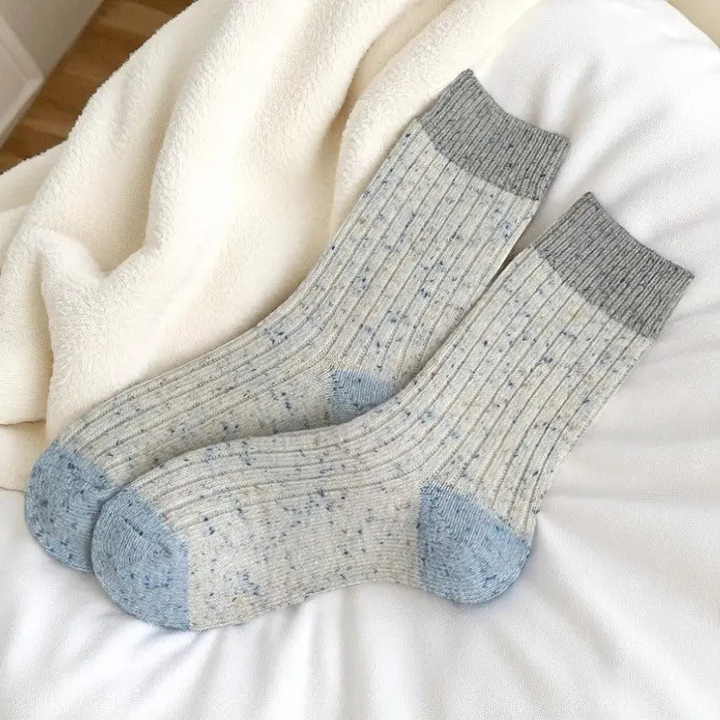Chaussettes en laine gris clair moucheté avec talon et bout bleu.