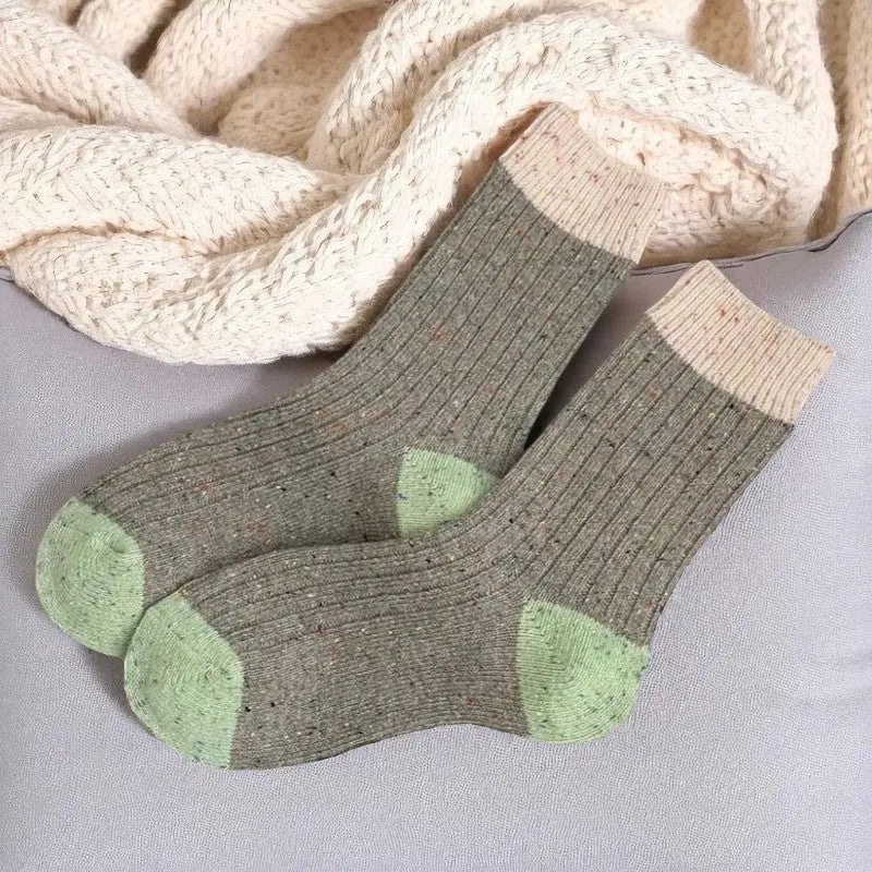 Paire de chaussettes en laine kaki avec bout et revers verts, posée sur un coussin.