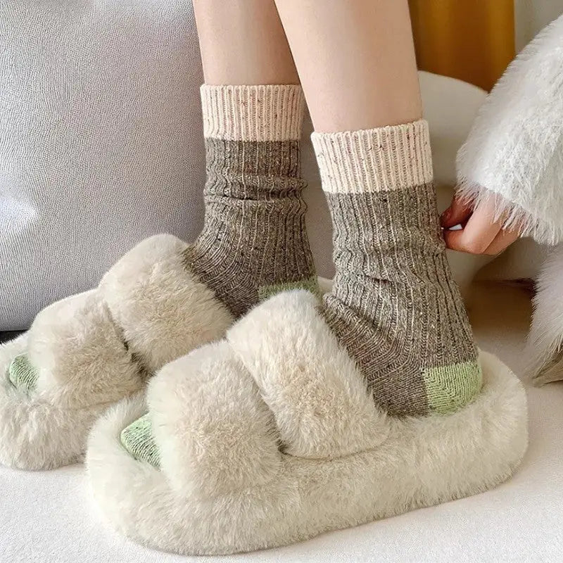 Chaussettes en laine portées, vertes avec revers beige et pantoufles en fourrure.