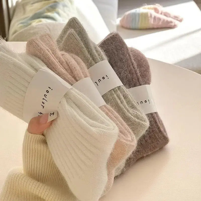 Lot de chaussettes cachemire femme tenues en éventail à la main, en teintes pastel et douces.