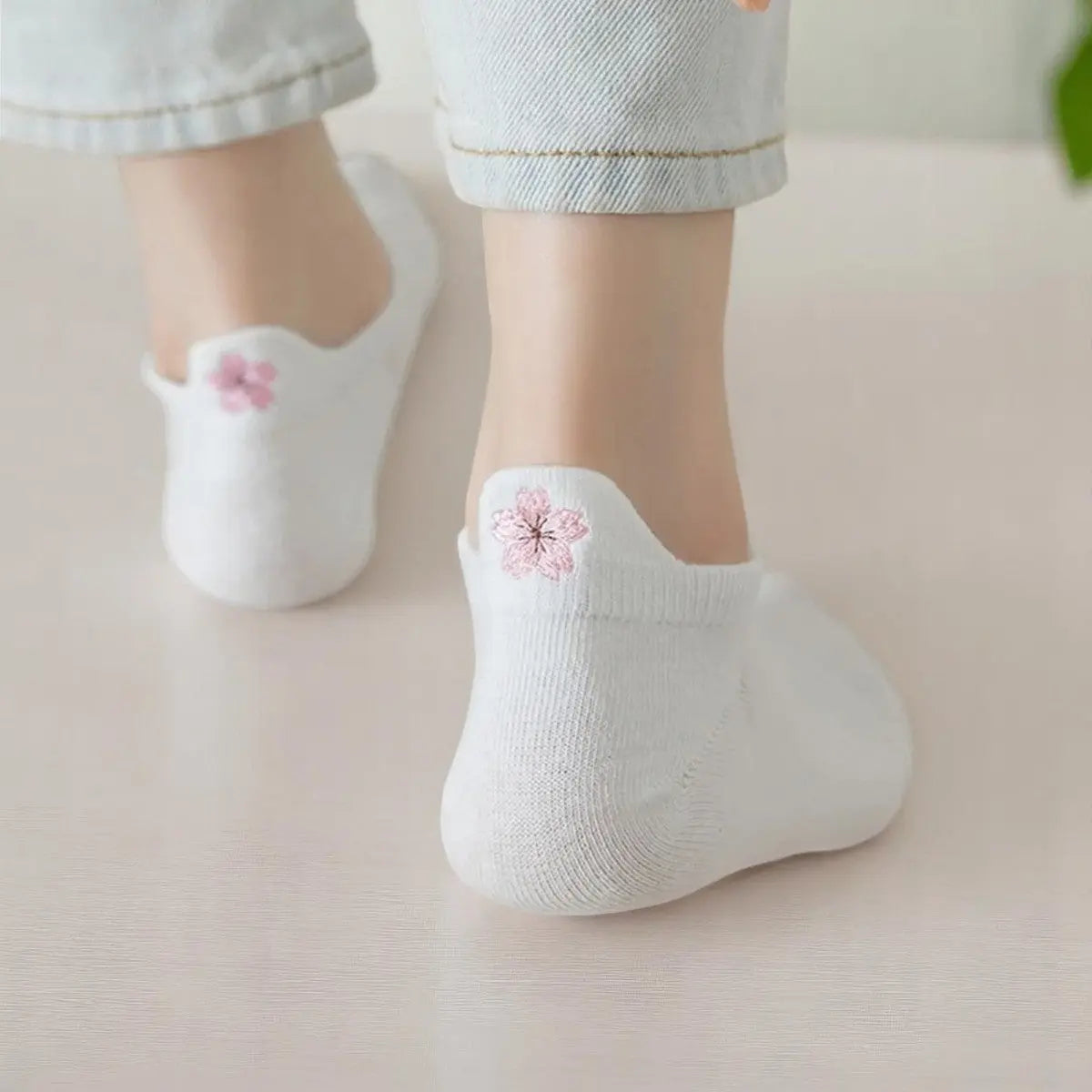 Socquettes blanches avec broderie fleur rose, portées avec un jean retroussé.
