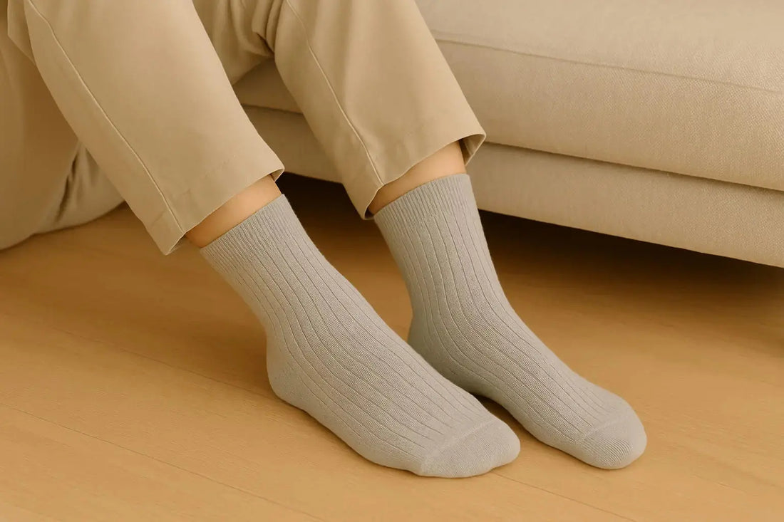 Personne assise portant des chaussettes grises côtelées en coton et bambou – confort et style au quotidien.