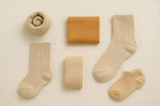 Ensemble de chaussettes beiges et ocre soigneusement pliées sur fond clair – collection minimaliste et de qualité.