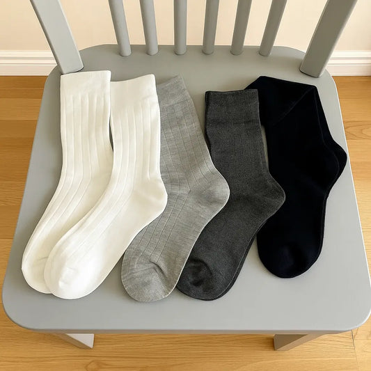 Quatre paires de chaussettes bambou femme alignées sur une chaise grise : blanc, gris clair, gris foncé et noir.