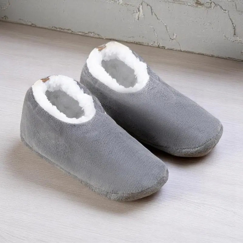 Chaussettes chaussons femme gris clair avec intérieur doux blanc, posées sur un sol clair.