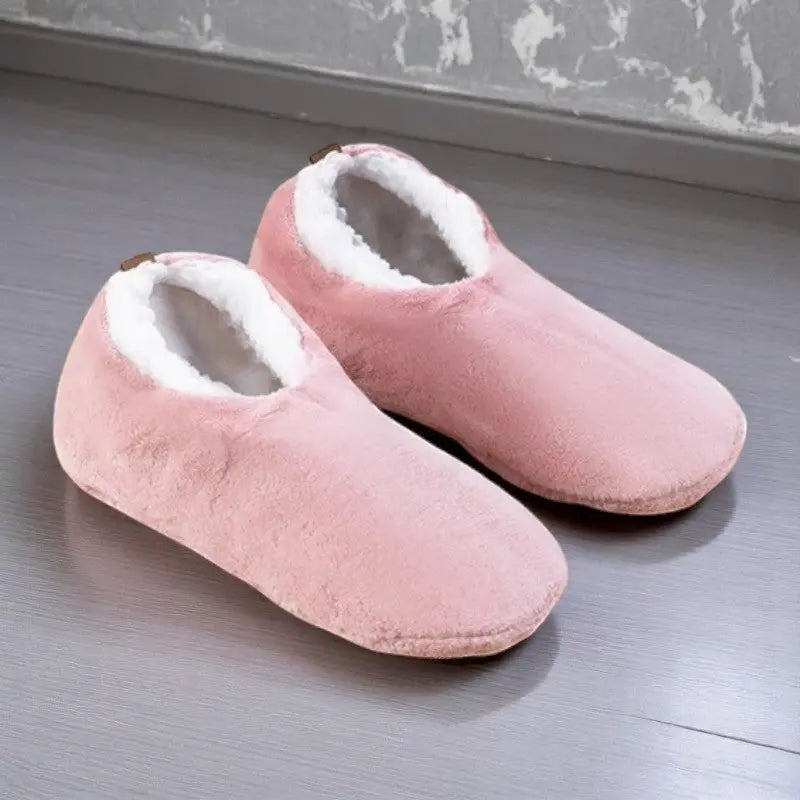 Chaussettes chaussons femme rose pastel avec doublure chaude blanche sur sol gris.
