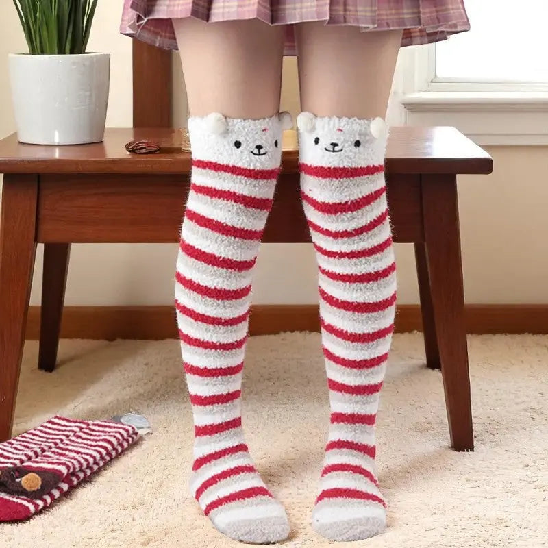 Chaussettes hautes rayées rouges et blanches avec tête d’ours blanc sur les genoux.