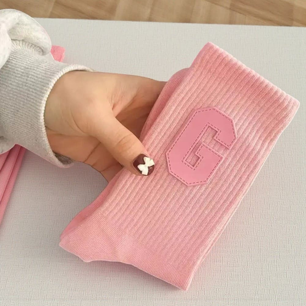 Chaussette rose femme avec logo G rose tenue en main.