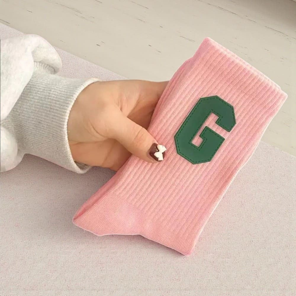 Chaussette rose pâle femme avec logo G vert décoratif.