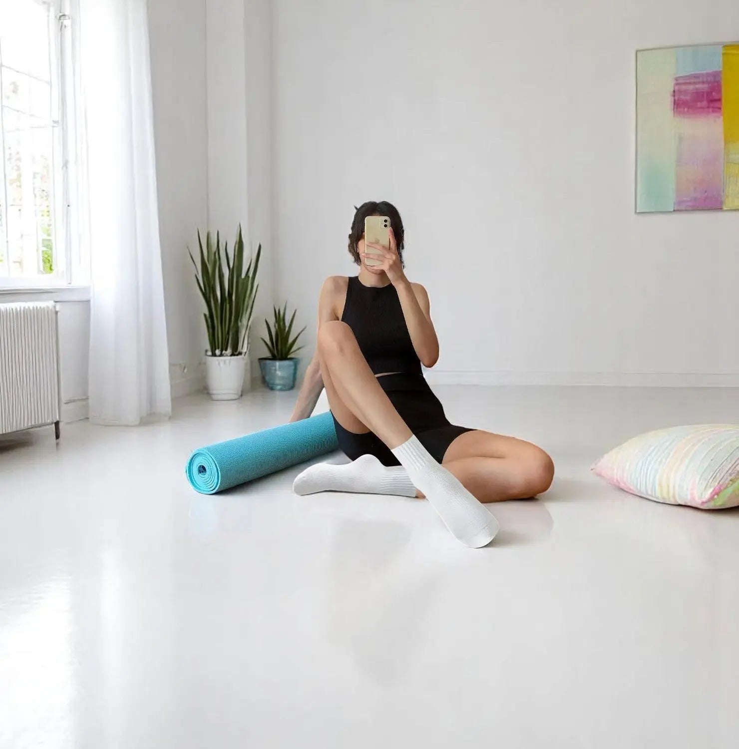 Femme en tenue de yoga portant des chaussettes antidérapantes blanches dans un studio lumineux.