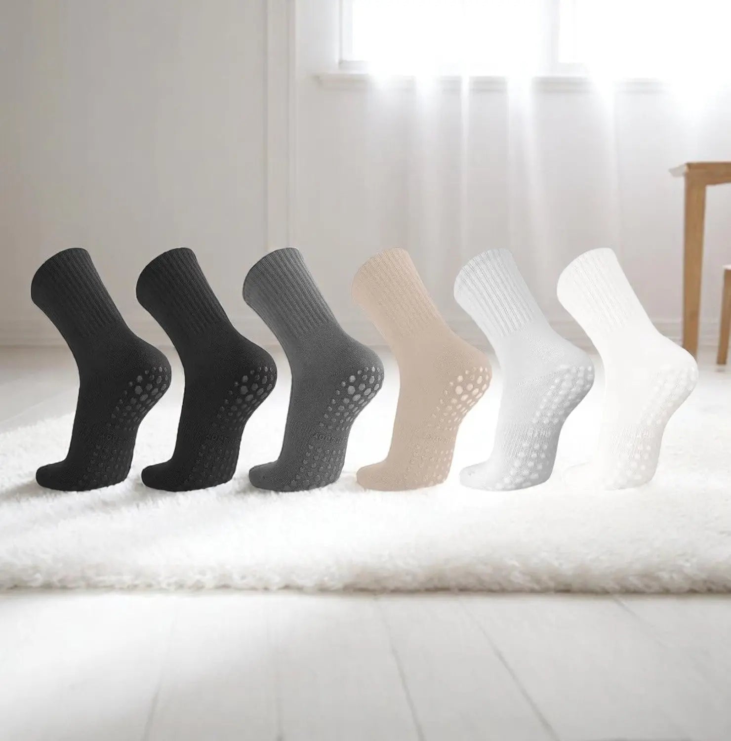 Chaussettes antidérapantes femme alignées sur un tapis beige dans un intérieur épuré.