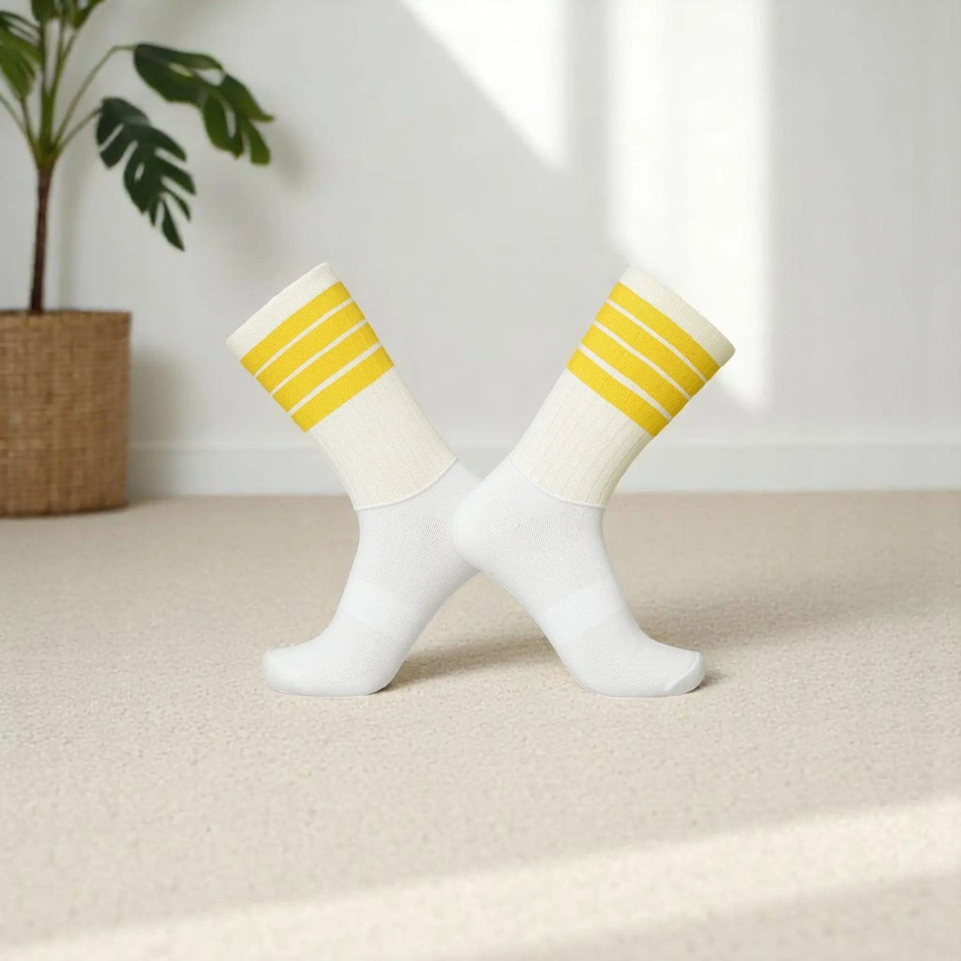 Chaussettes antidérapantes blanches à rayures jaunes croisées sur fond doux.