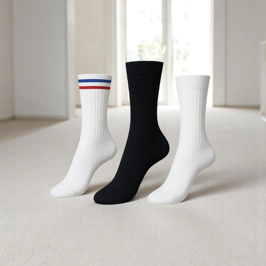 Trois chaussettes antidérapantes pour homme rangées sur fond gris : une blanche à rayures bleue et rouge, une noire et une blanche classique.