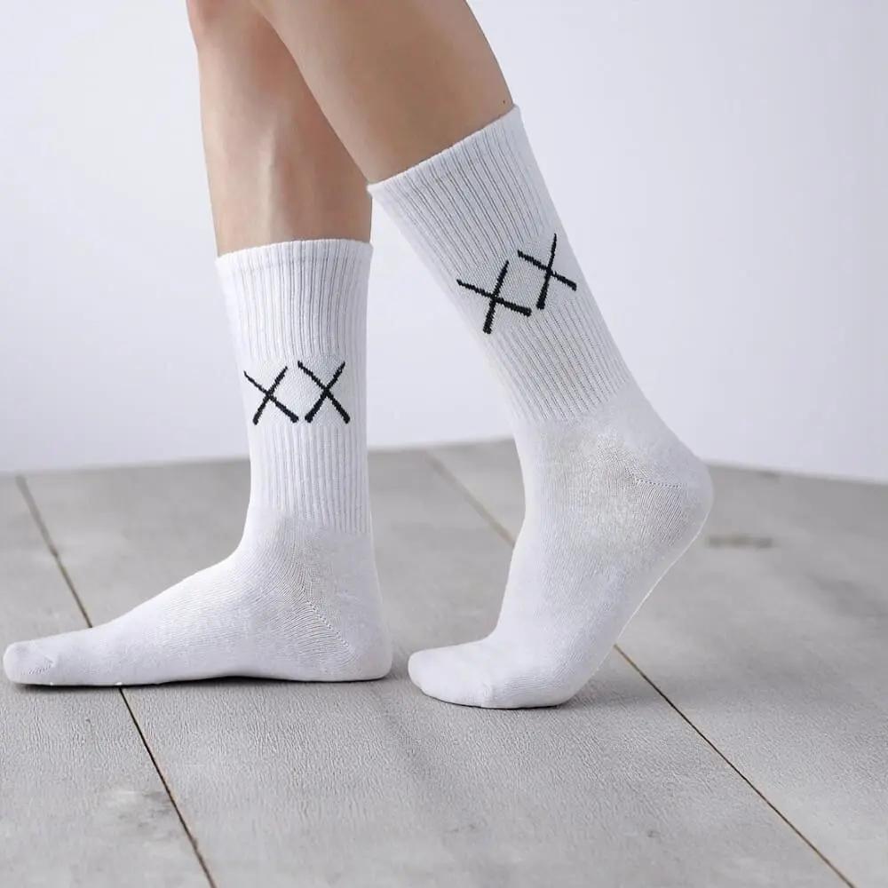 Chaussettes blanches homme portées, design minimaliste avec double XX noir, tissu doux et extensible.