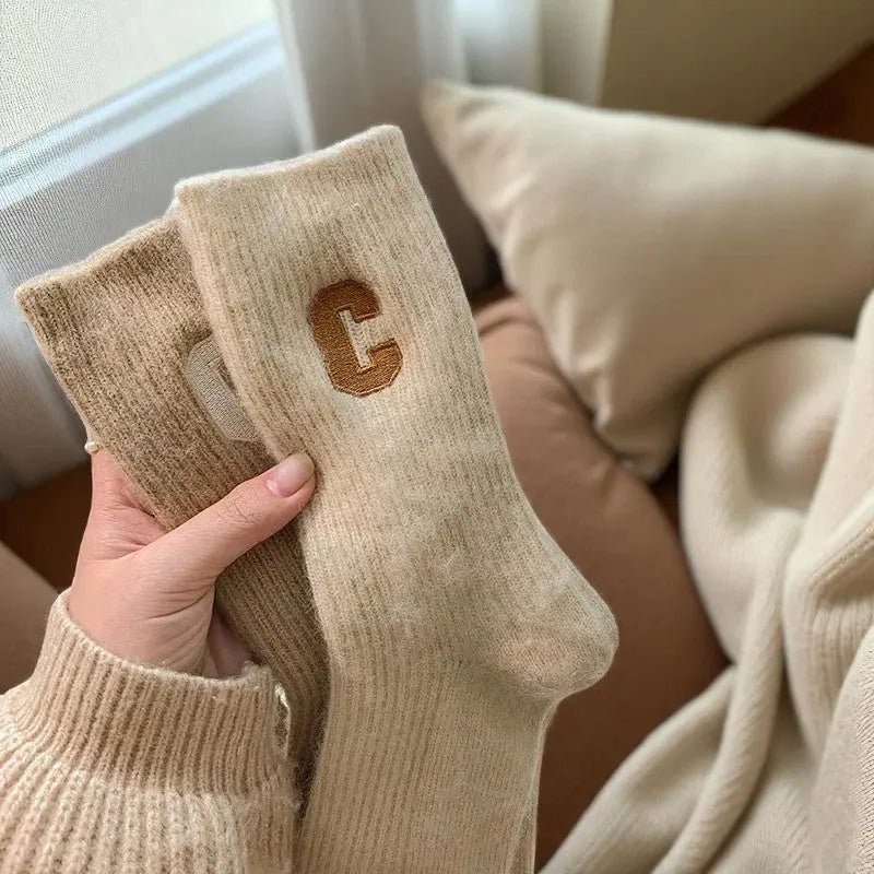 Chaussettes cachemire beiges pour femme avec lettre camel tenues à la main.