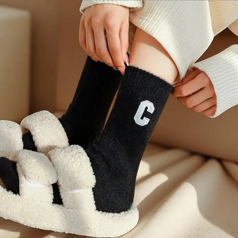 Chaussettes cachemire noires pour femme portées avec des claquettes moelleuses.