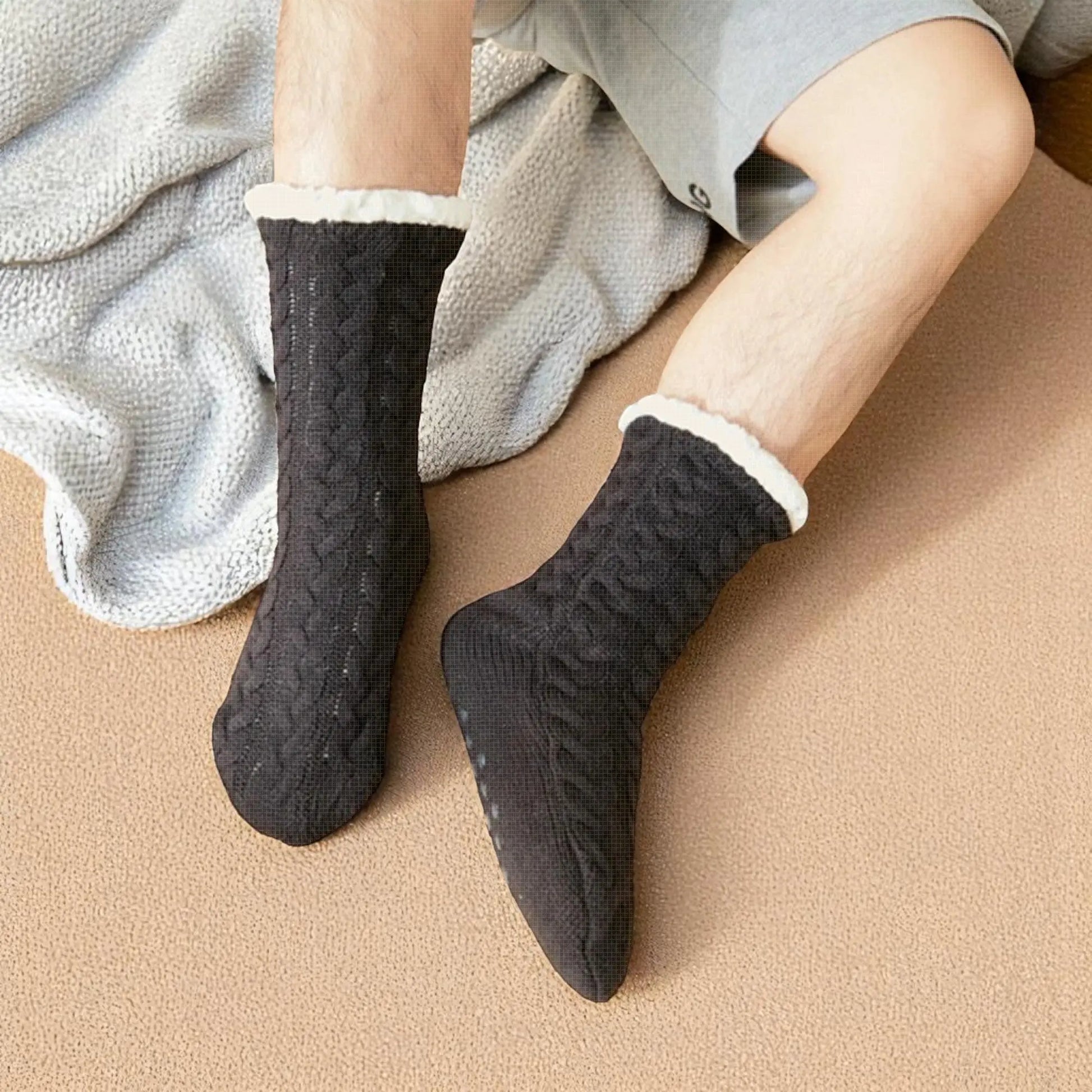 Homme portant des chaussettes chausson noires confort sur tapis beige.