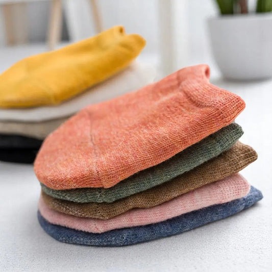 Zoom sur un lot de chaussettes invisibles demi-pied empilées, avec une chaussette orange en premier plan.