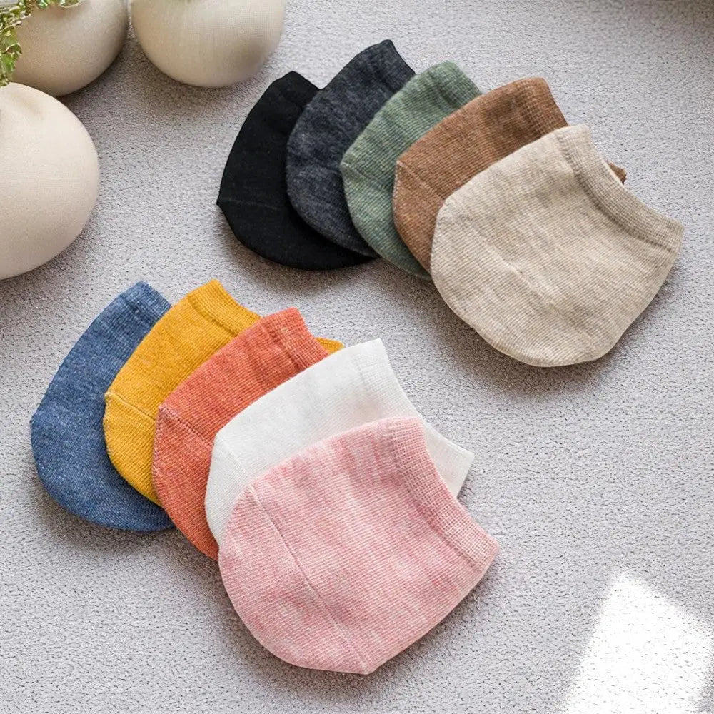 Chaussettes demi-pied alignées en éventail sur tapis texturé, en multiples couleurs.