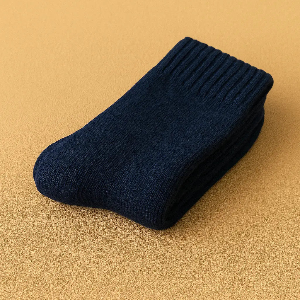 Chaussettes en cachemire bleu marine pour homme, posées sur un tapis beige élégant.