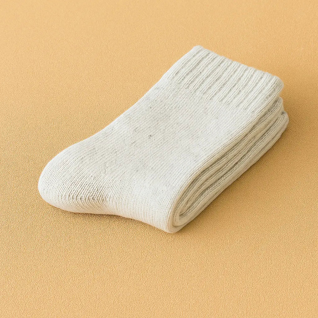 Paire de chaussettes en cachemire gris chiné pour homme, pliée avec soin sur un tapis beige texturé.
