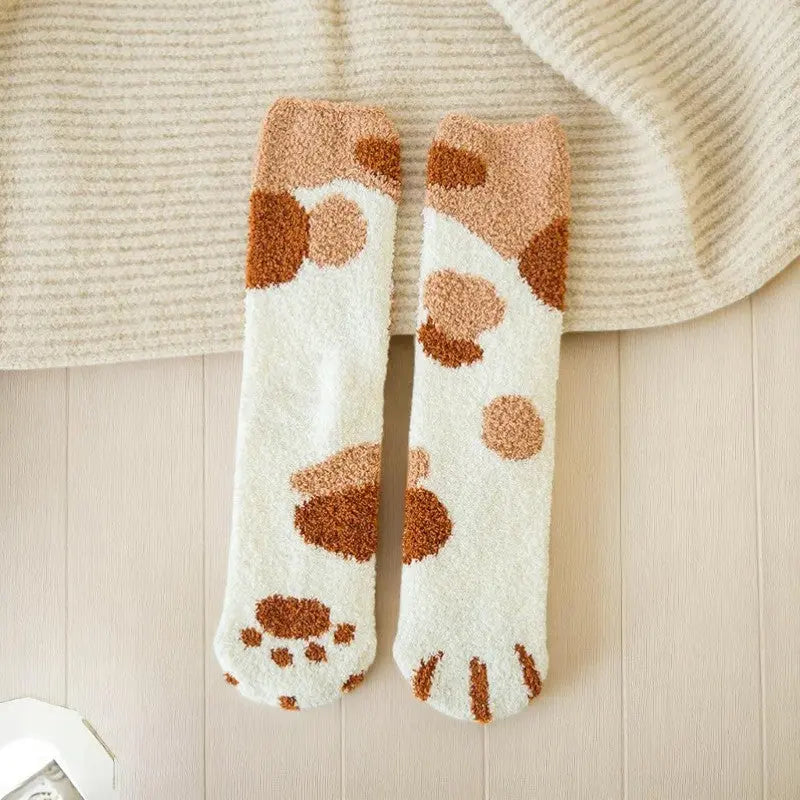 Paire de chaussettes hiver femme motif patte de chat blanc et marron sur fond doux beige.