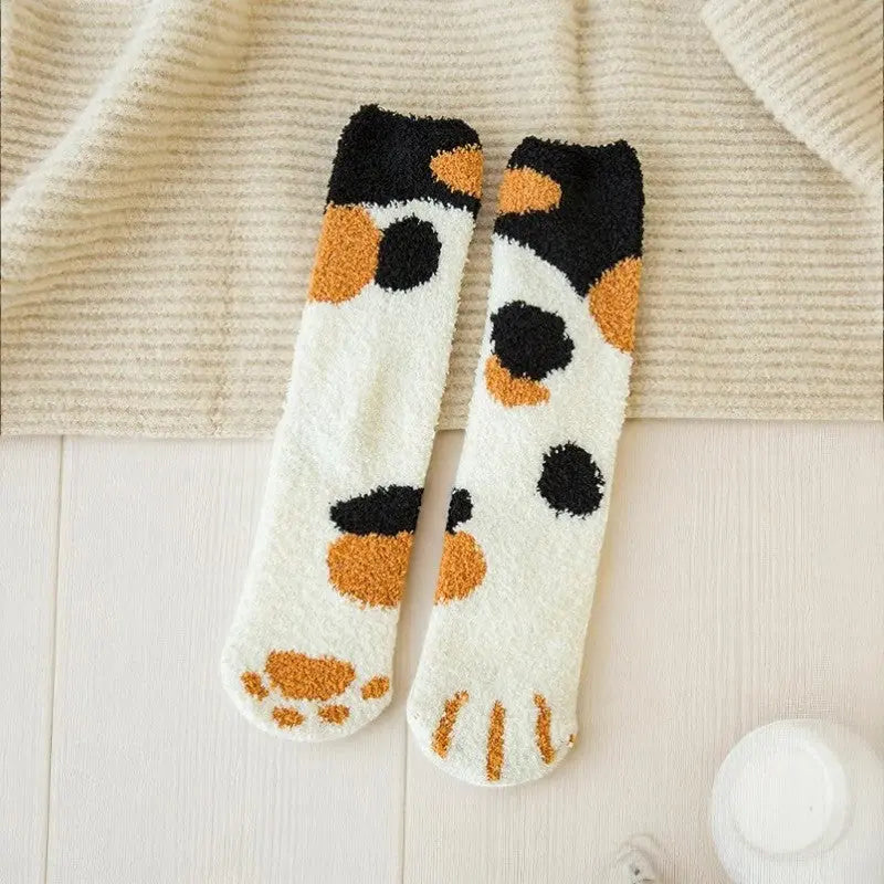 Chaussettes chaudes femme motif tricolore calico posées près d’un plaid beige.