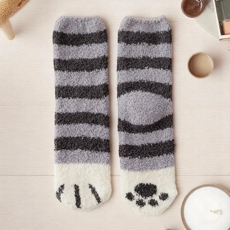 Chaussettes rayées noires et grises posées à plat avec ambiance cocooning.
