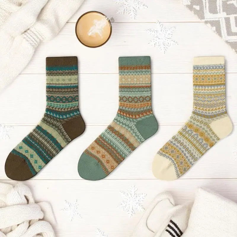 Chaussettes chaudes femme avec imprimés nordiques présentées avec un café latte et des flocons en papier.