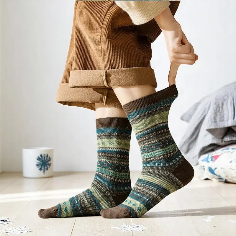 Chaussettes femme motifs verts et turquoise portées debout dans un décor chaleureux et lumineux.