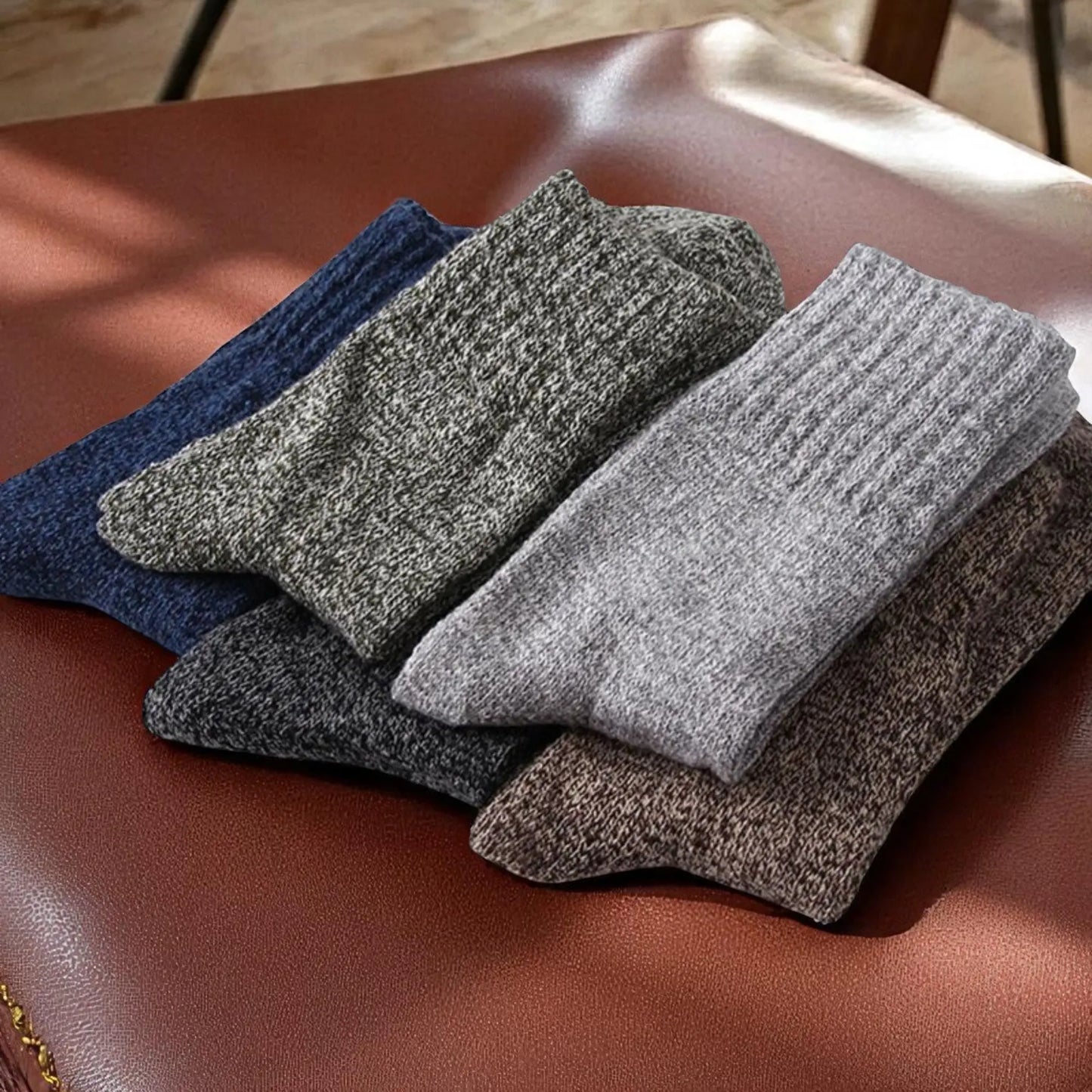 Lot de chaussettes d'hiver pour homme pliées, posé sur un fauteuil en cuir.