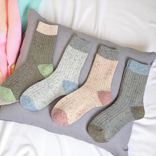 Ensemble de quatre paires de chaussettes en laine posées sur un coussin.