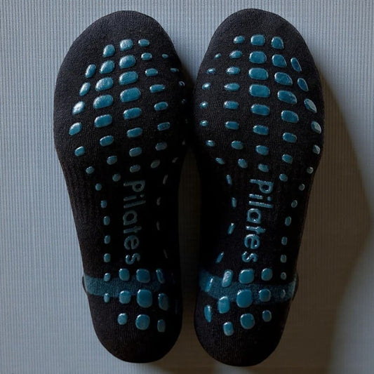 Semelles antidérapantes de chaussettes Pilates noir et bleu pour adhérence maximale.