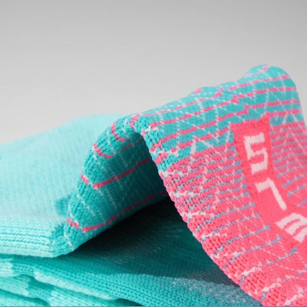 Zoom sur la texture des chaussettes running turquoise, tissu technique respirant avec renforts tissés.