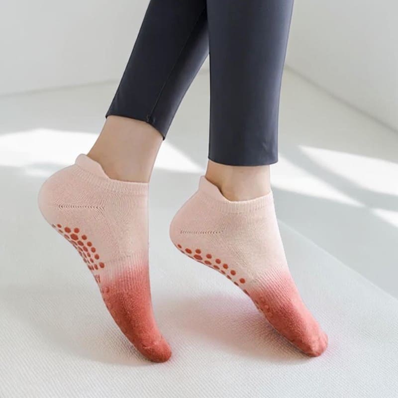 Chaussettes yoga portées par une femme – dégradé rose corail antidérapant.