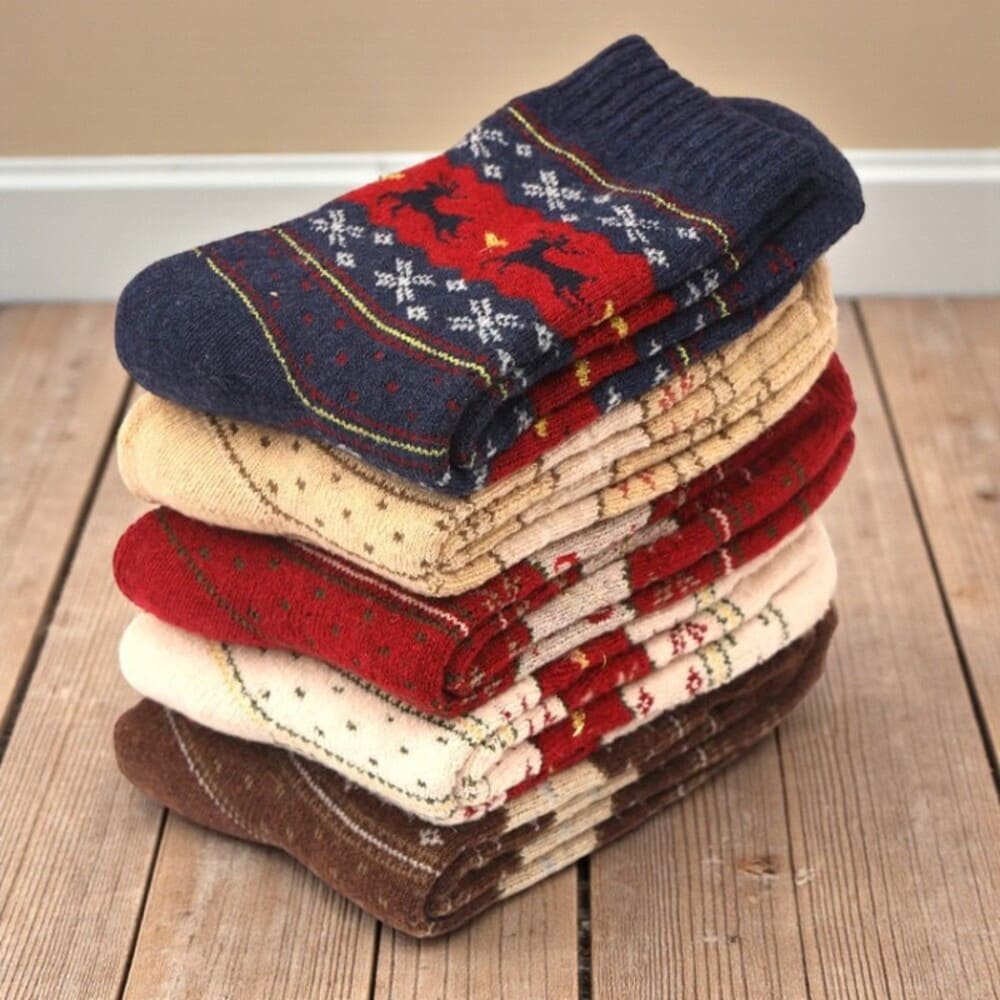 Paires de chaussettes hiver femme rouges et beiges pliées, motif nordique chaleureux.