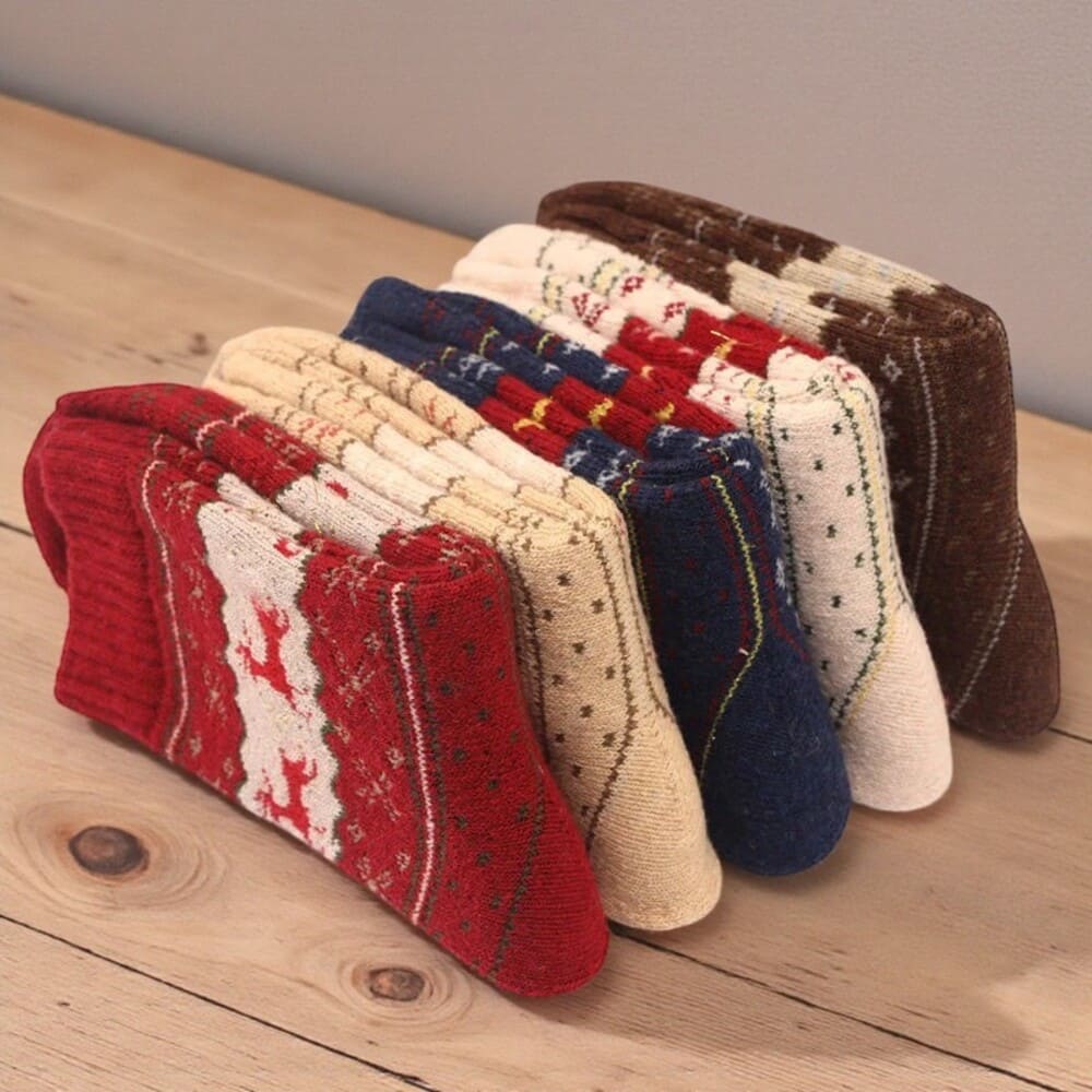 Chaussettes hiver femme alignées sur une table, design cosy motif renne.