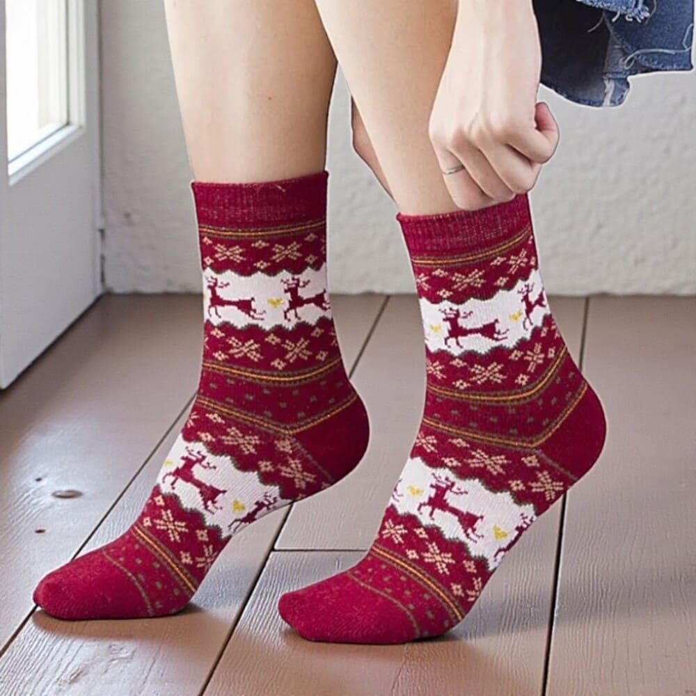 Chaussettes rouges femme portées, motif renne blanc style hivernal.
