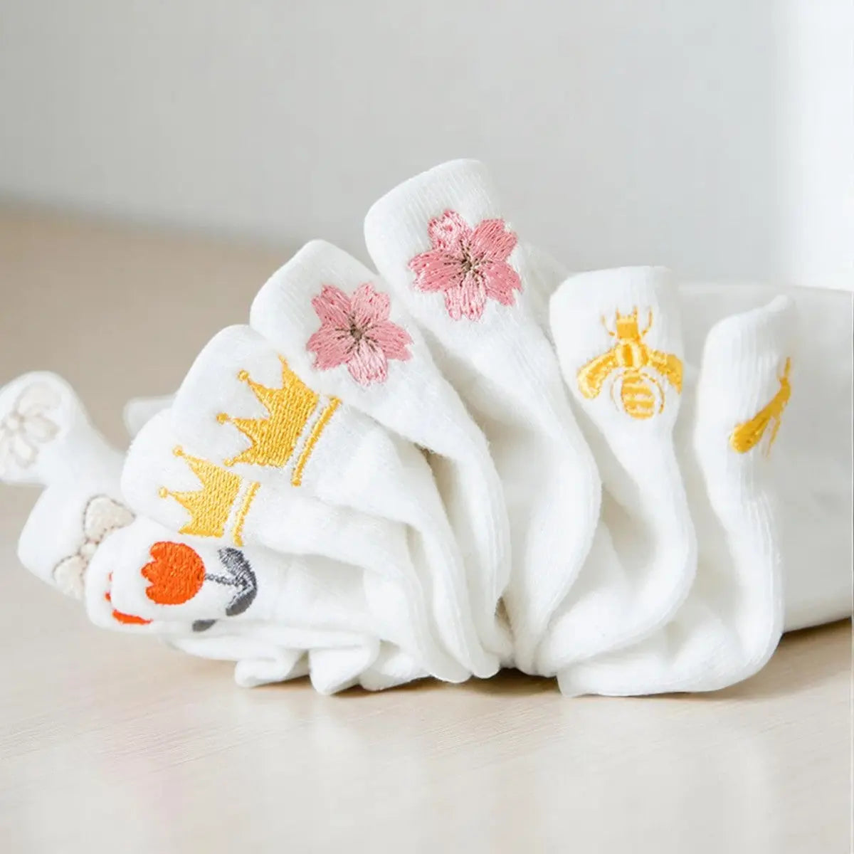 Lot de socquettes brodées avec des motifs variés : fleurs, abeille et couronne.